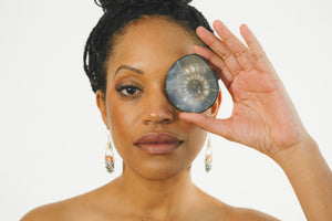Beautiful women wearing Justicia Artisan Jewlelry Earrings and holding an ammonite